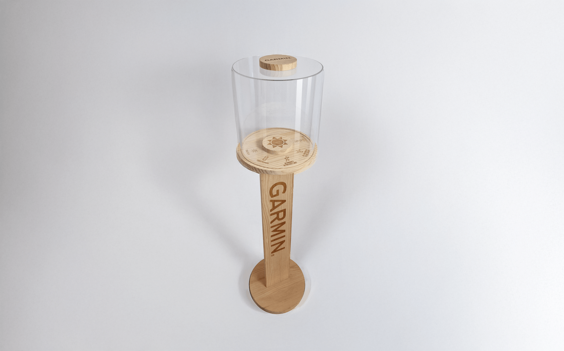 Wooden display showcase with cylindrical transparent cover and Garmin logo engraved on the pedestal.