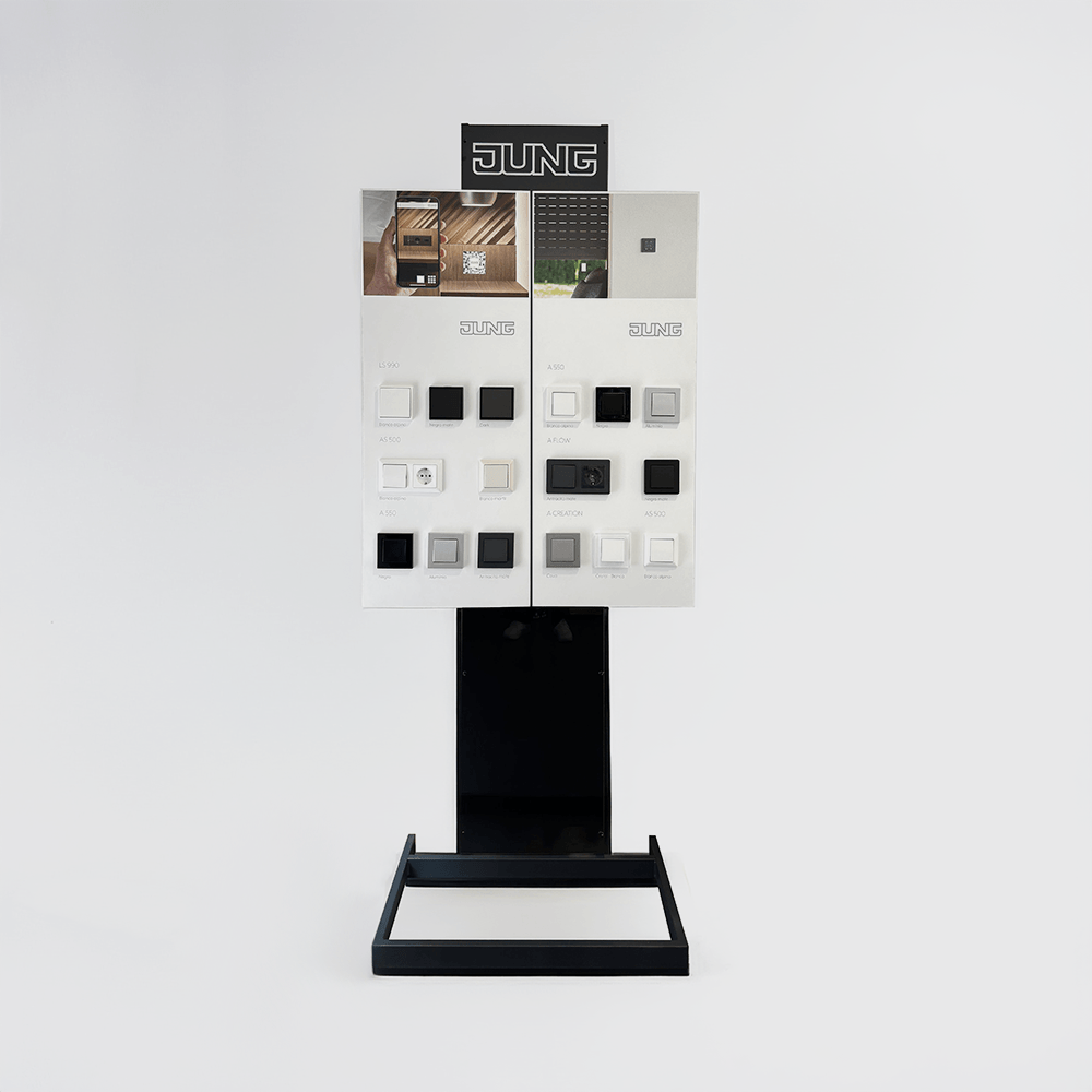 Expositor metálico y panel frontal con muestras reales de mecanismos eléctricos JUNG.
