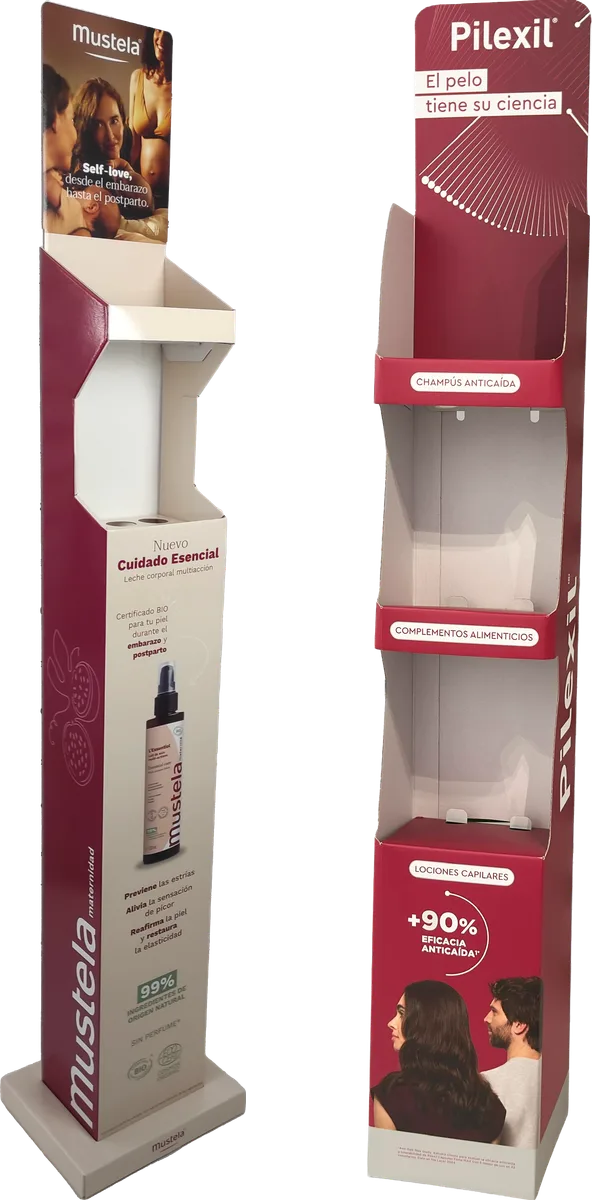 Two empty cardboard floor displays, the Mustela maternity one with a photo header and a top tray, and the burgundy Pilexil one with three levels labelled for shampoos, supplements and lotions