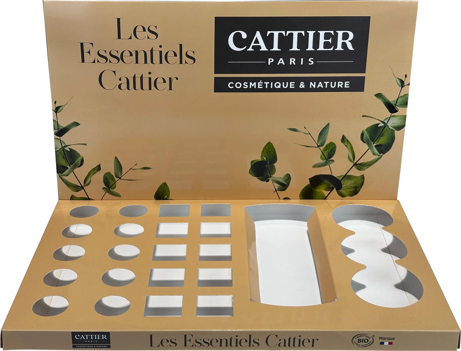 Plateau de comptoir Cattier Les Essentiels couleur sable, vide, avec des alvéoles découpées rondes, rectangulaires et ondulées pour chaque format de produit, et un panneau arrière orné de branches d'eucalyptus
